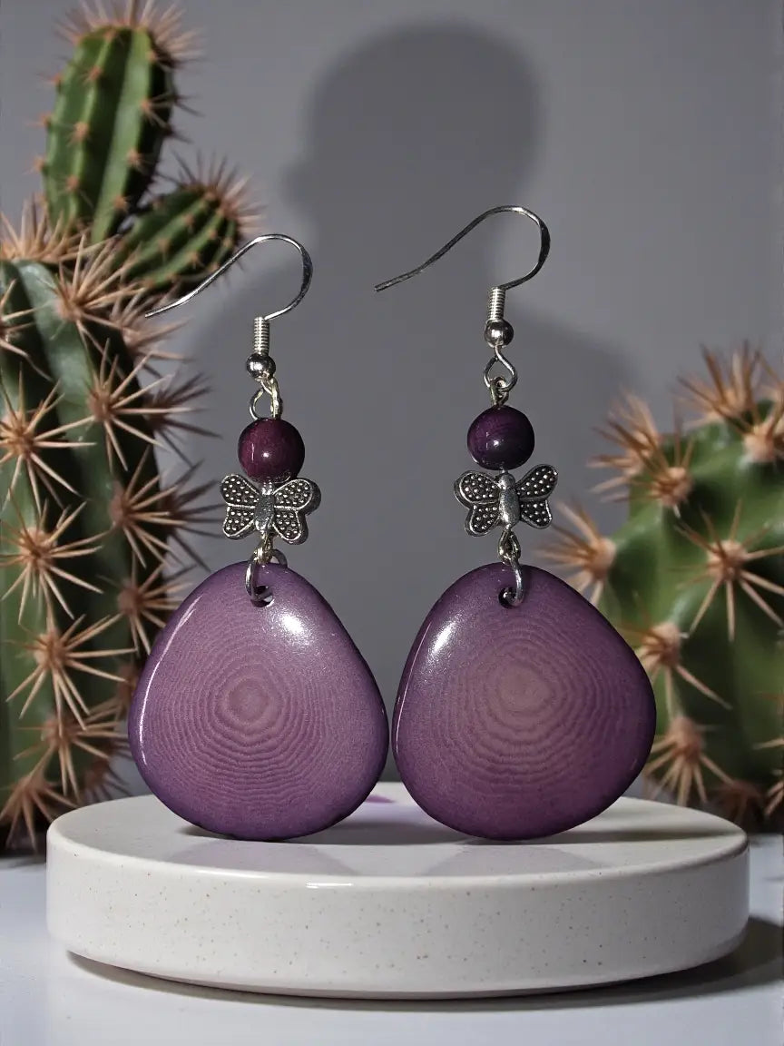 Heather purple sliced tagua nut earrings with glossy teardrop shapes silver butterfly charms and small purple beads