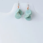 Delicate mint green layered tagua nut petal earrings with subtle sheen on silver hooks tied by orange cord