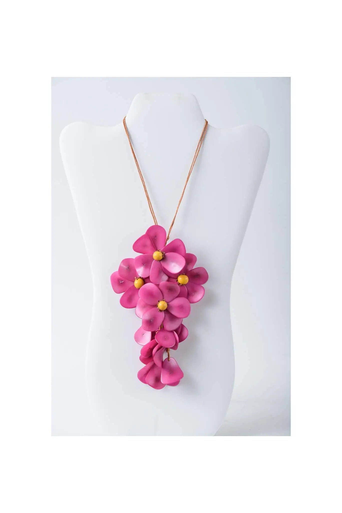 A vibrant pink fuchsia holly pendant flower tagua necklace with yellow centers on a delicate gold-toned chain