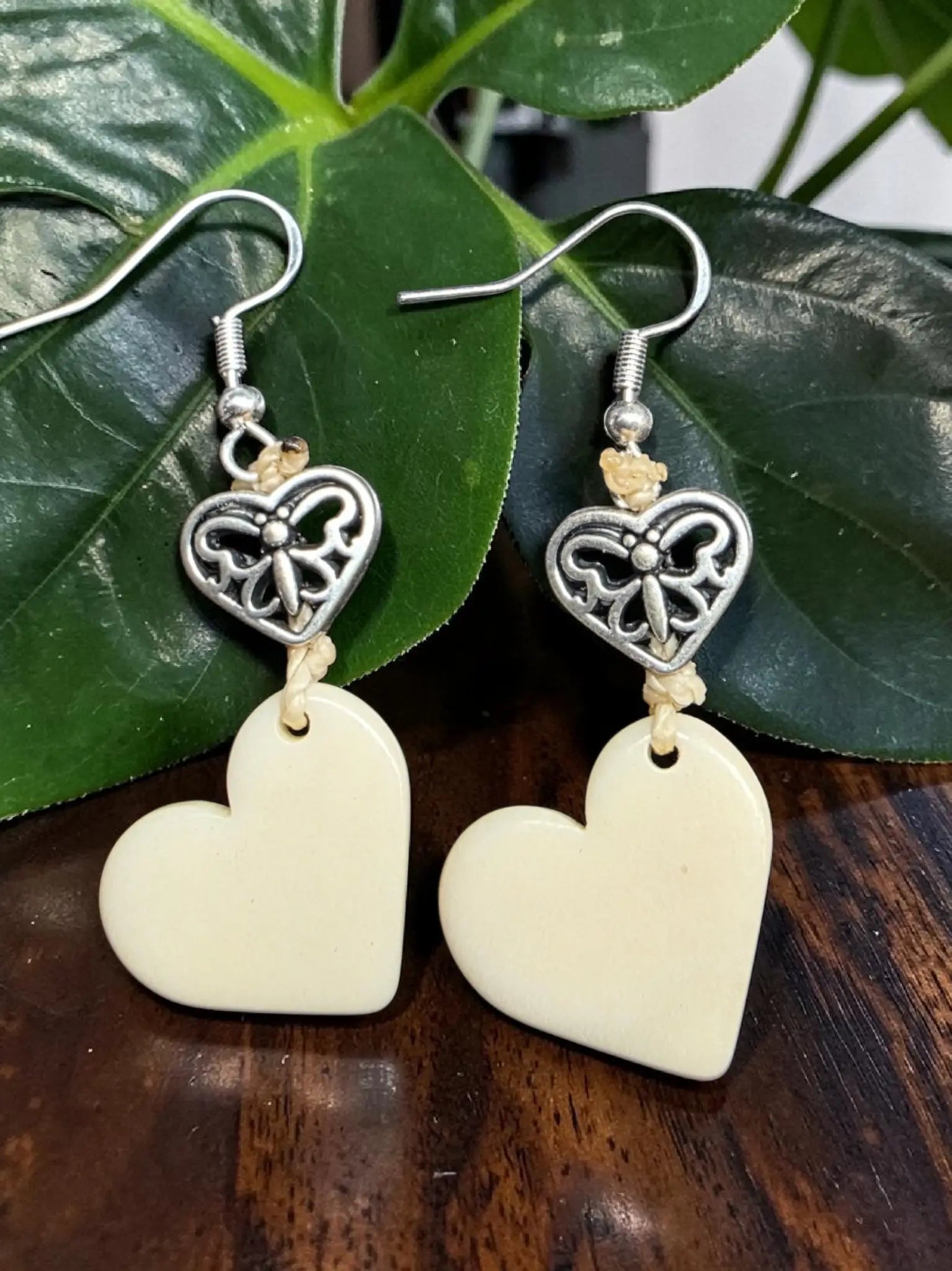 Ivory tagua heart carved vegetable ivory cream earrings with silver butterfly charms hanging from delicate hooks