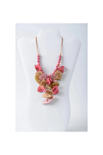 A layered tagua necklace with cascading pink and beige button-like discs on a delicate beaded chain in coastal aqua