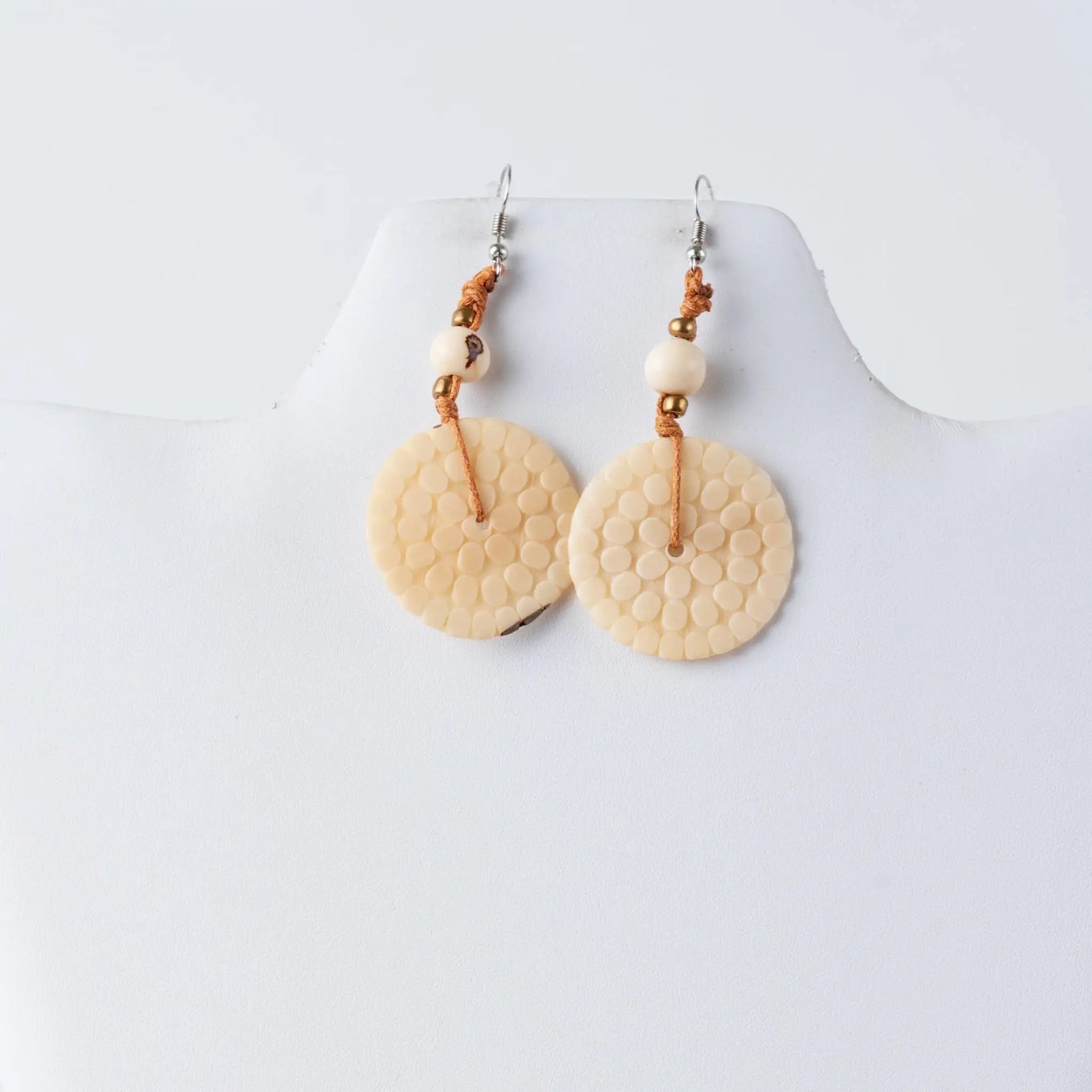 Cream-colored engraved tagua earrings with honeycomb texture, beads, and braided cord accents from lana eco-chic