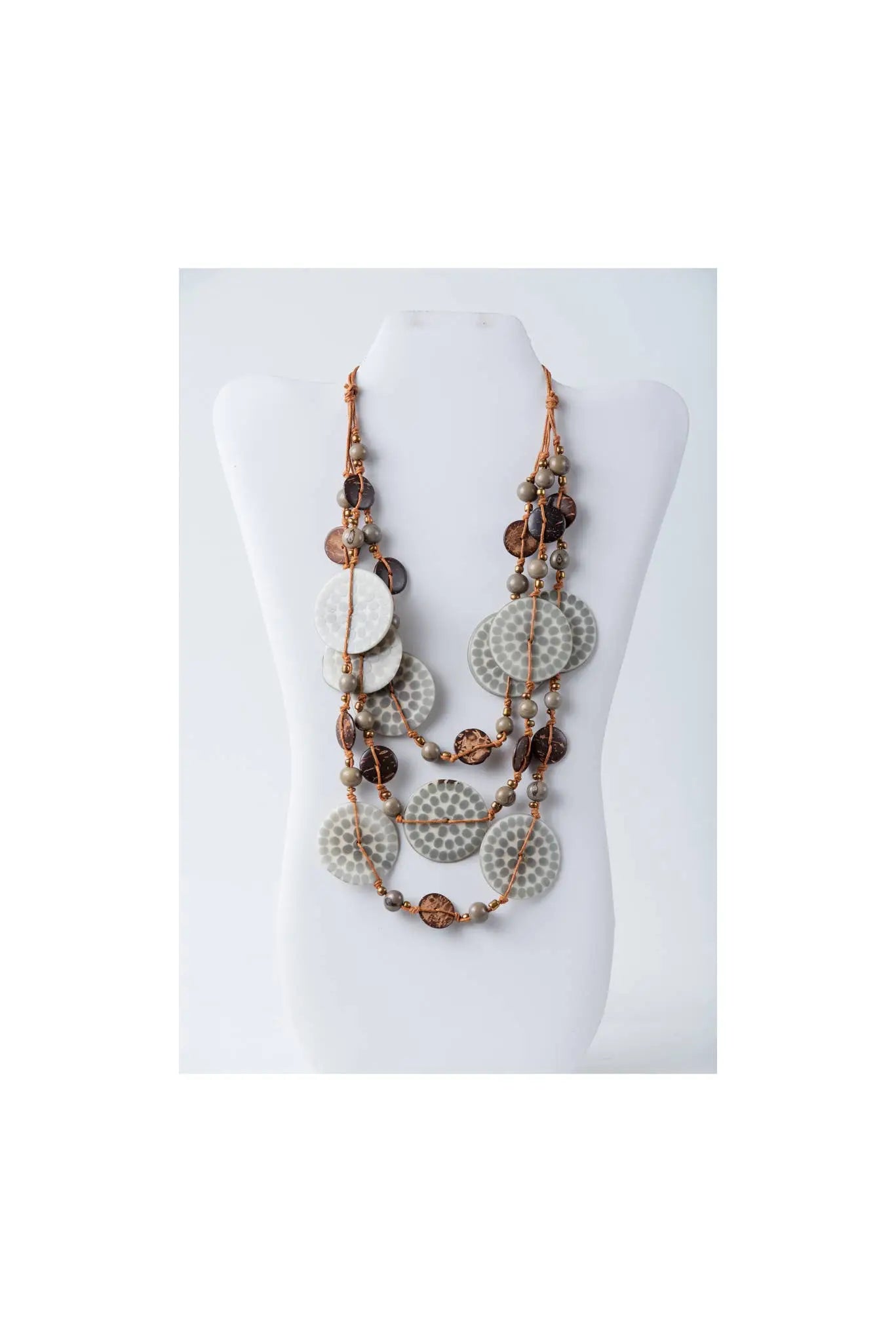 Layered necklace with engraved tagua circular discs in muted gray and warm brown on a braided cord with metallic beads