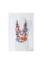 A coral and light blue layered necklace with engraved tagua and metallic beads in the lana eco-chic style