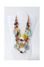 A layered necklace with yellow green and blue engraved tagua beads and brown wooden accents from lana eco chic