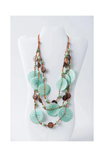 A layered turquoise and copper necklace with engraved tagua beads and textured circular discs from lana eco-chic