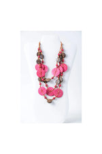 A vibrant pink and brown layered necklace with engraved tagua circular beads on a woven coconut cord