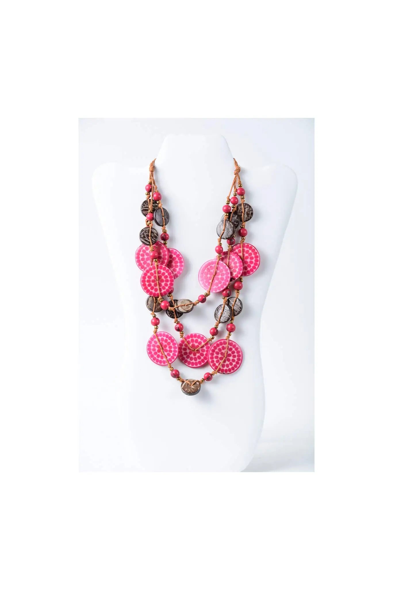 A vibrant pink and brown layered necklace with engraved tagua circular beads on a woven coconut cord