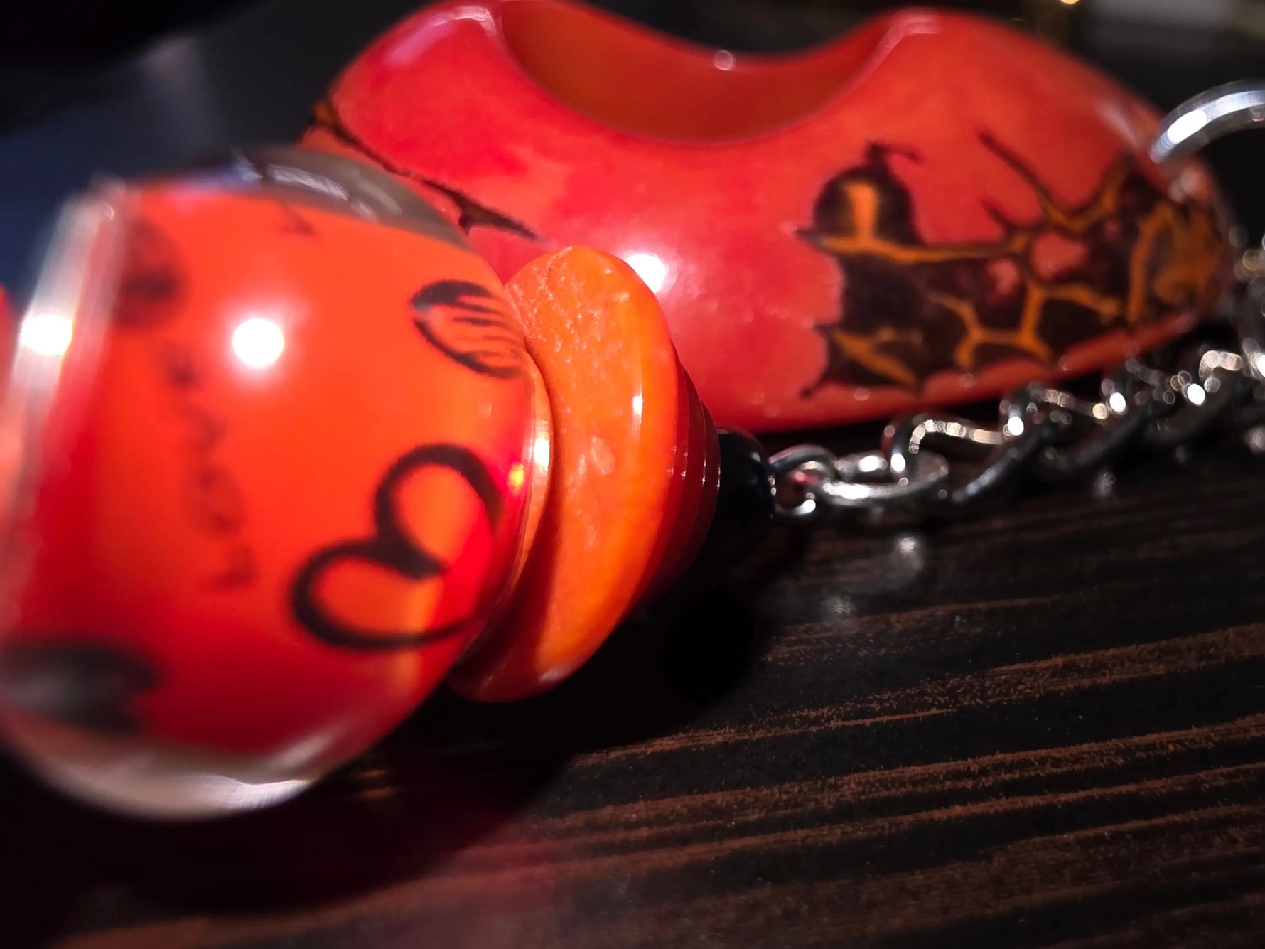 Vibrant red ceramic large carved and polished tagua bag charm with glossy finish and black silhouette designs