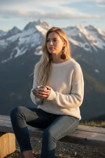 A woman wearing a cream-colored textured knit sweater with lightweight chocolate mocha tagua slice swirl bird earrings