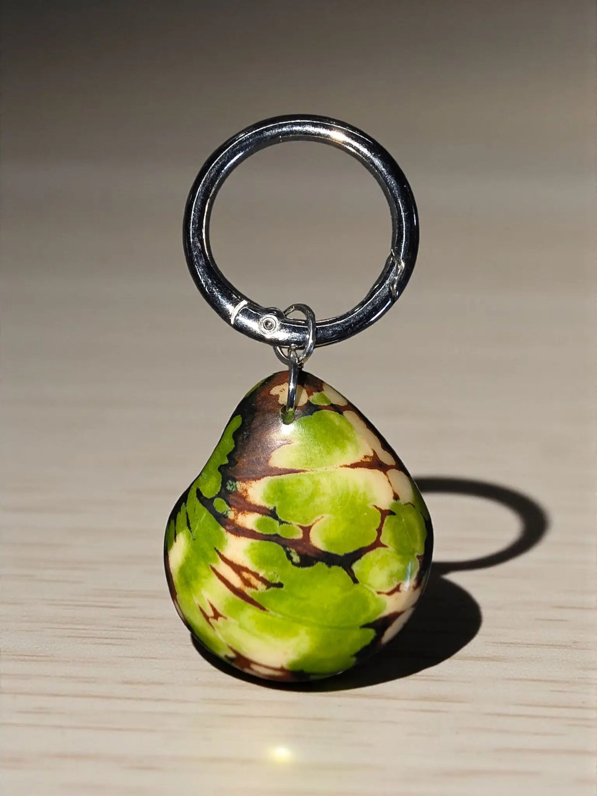 A glossy lime green key chain with a vibrant green and brown marbled pattern bag charm