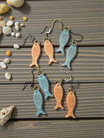Little fishes katie earrings celeste feature glossy enamel fish shapes in soft peach and light blue with detailed scales