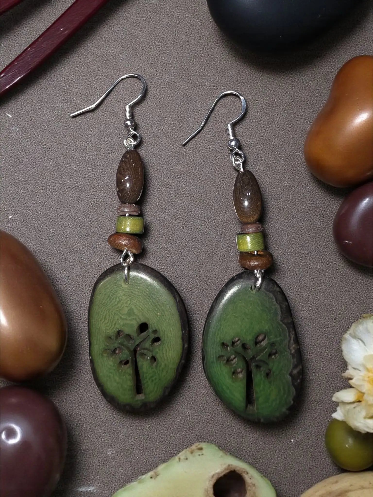 Green tree-themed oval laser cutout tagua slice earrings with brown beads and silver hooks