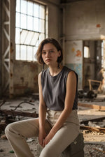 A woman wearing dark gray top and beige pants sits in an industrial space wearing long black tagua big bead tube earrings with wood bead accents