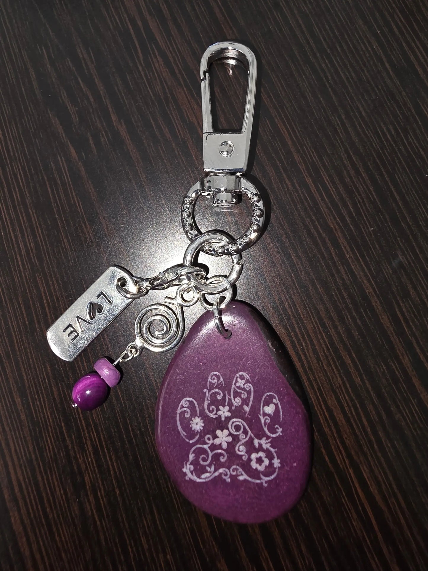 Purple teardrop-shaped tagua keychain with white floral engraving and love charm from puppy love small bag charm