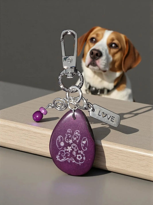 Purple teardrop-shaped tagua bag charm with white floral paw print design silver love tag and purple beads