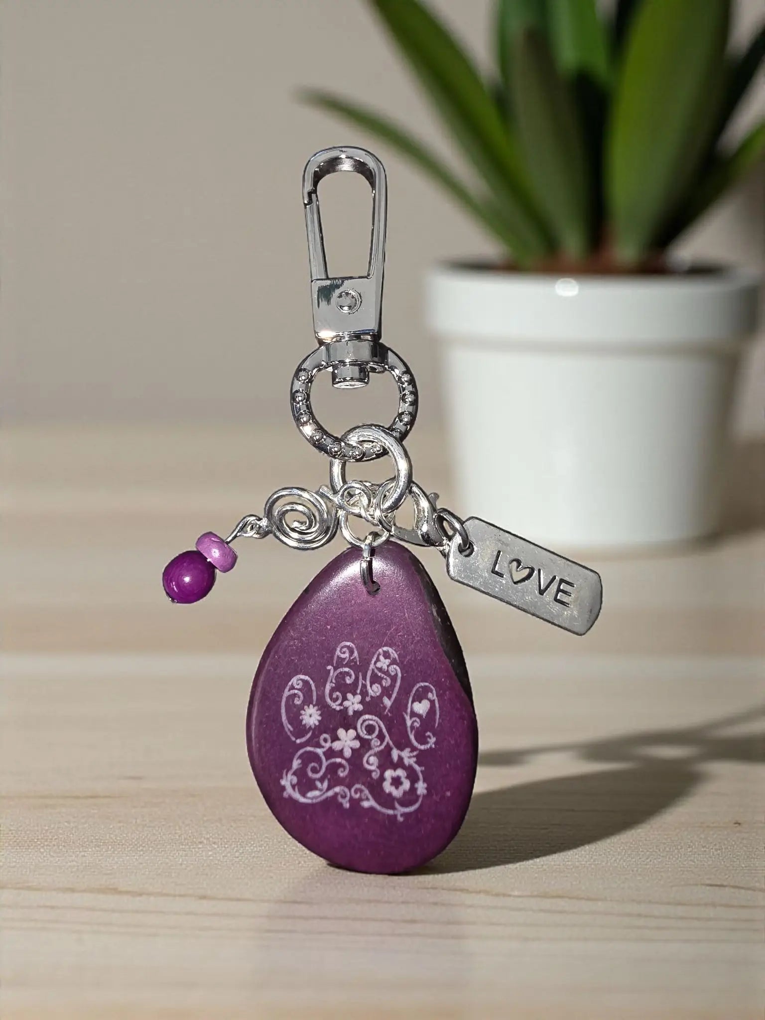 Purple teardrop-shaped wooden keychain with white handprint floral design silver love tag and purple beads for bag charm
