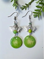 Green butterfly-shaped vegetable ivory earrings with silver-toned metal wings and marbled turquoise disc pendant