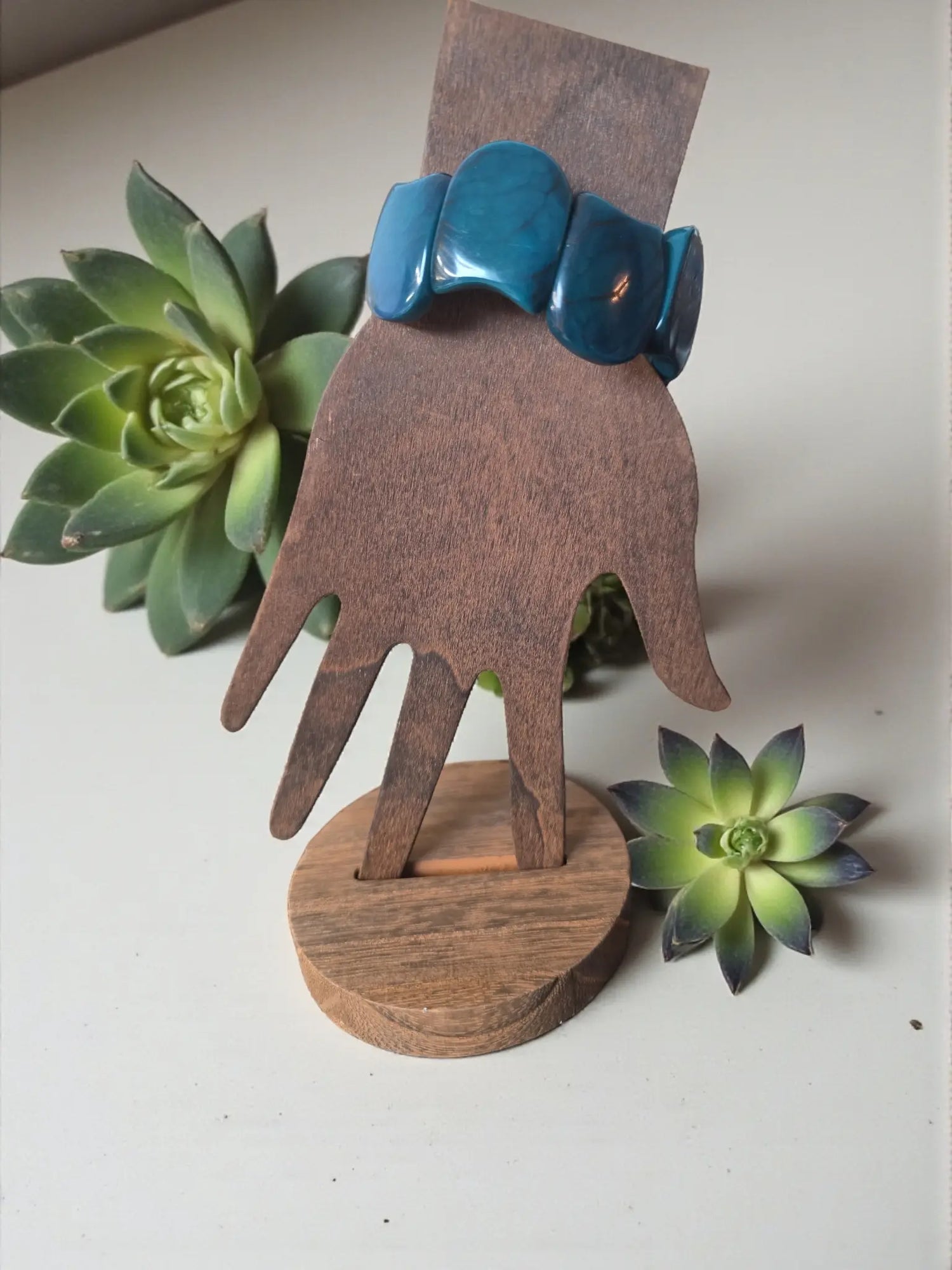 Vibrant turquoise marble teal blue carved tagua nut resin seed bracelet displayed on wooden hand stand forest seed bracelet