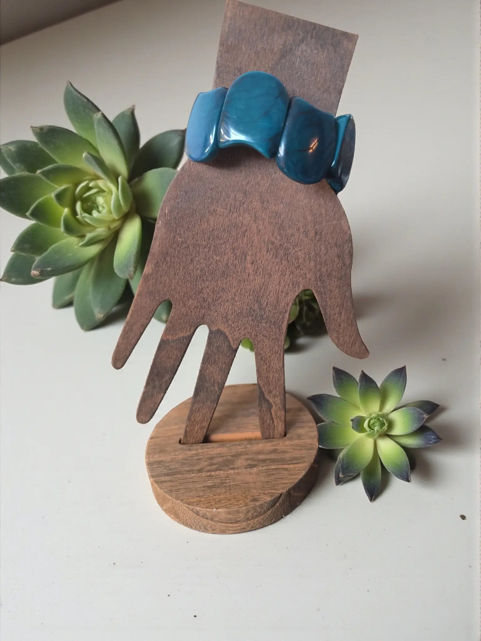 Vibrant turquoise marble teal blue carved tagua nut resin seed bracelet displayed on wooden hand stand forest seed bracelet