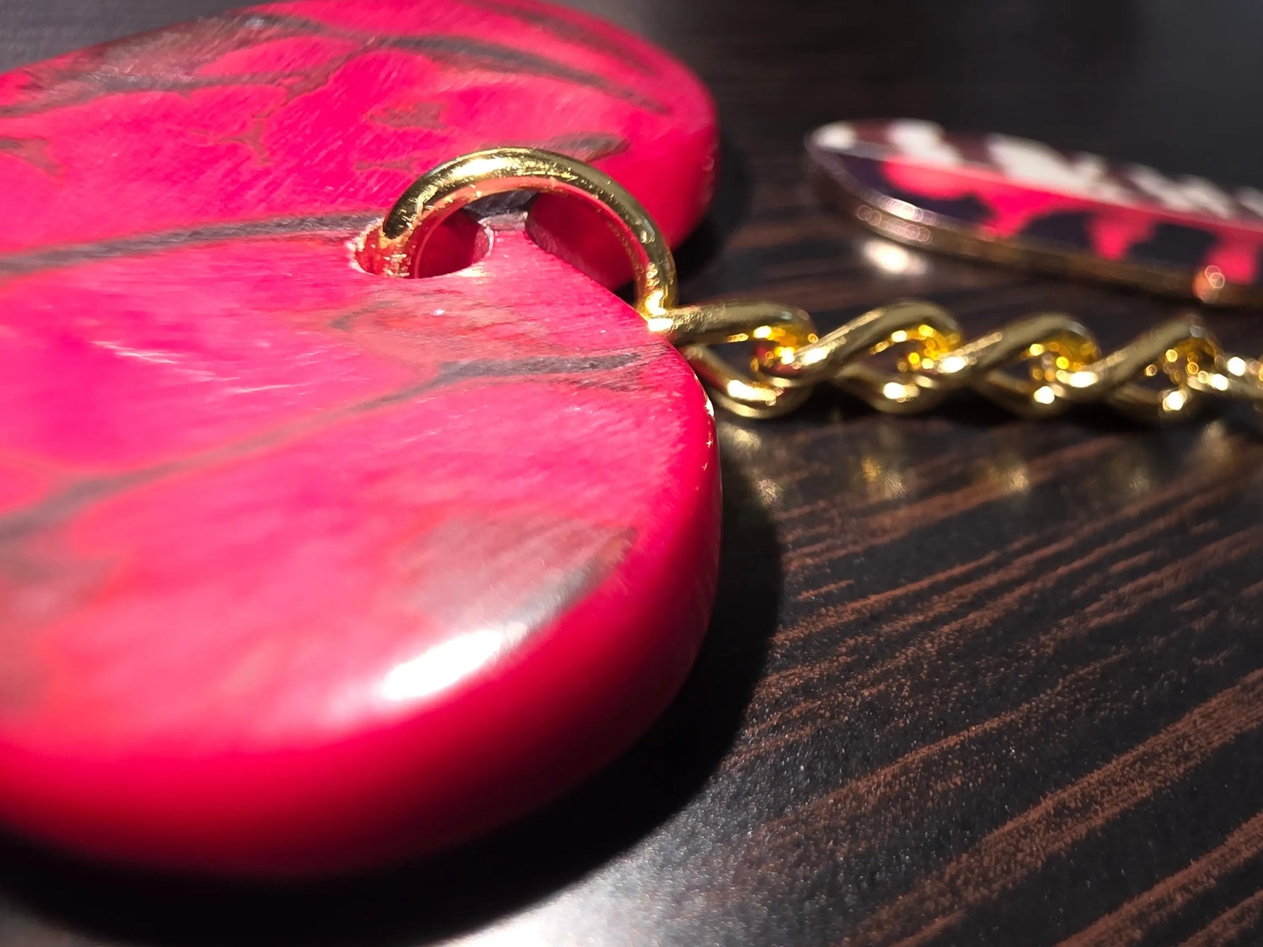 Vibrant pink heart-shaped wooden pendant with gold metal ring and chain for marbled red and black carved heart keychain