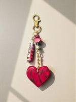 A vibrant red and black marbled heart tagua charm with gold chain for bags or keychains