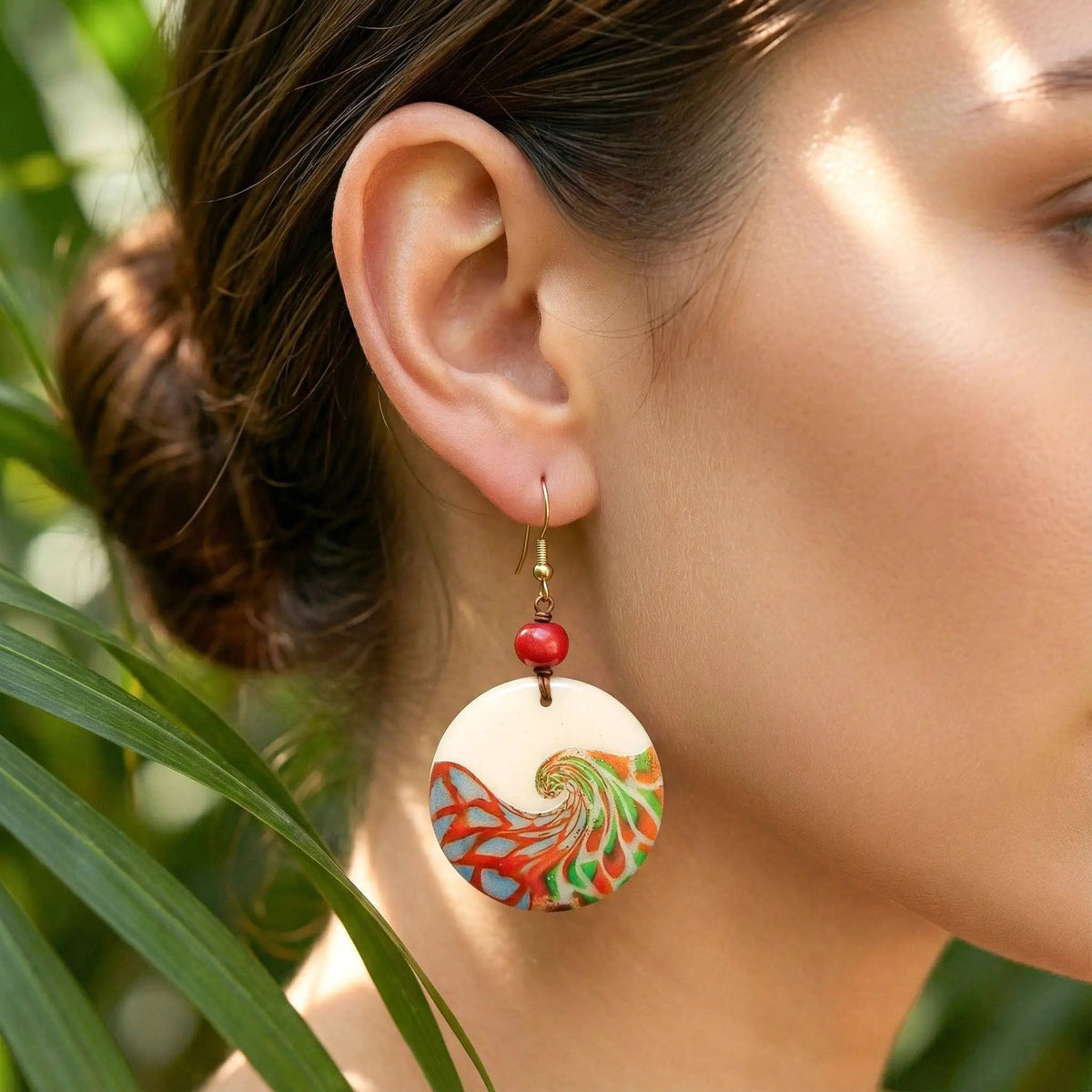 Mauren earrings vibrant circular tagua nut earring with swirling red green and orange design on gold-toned hook