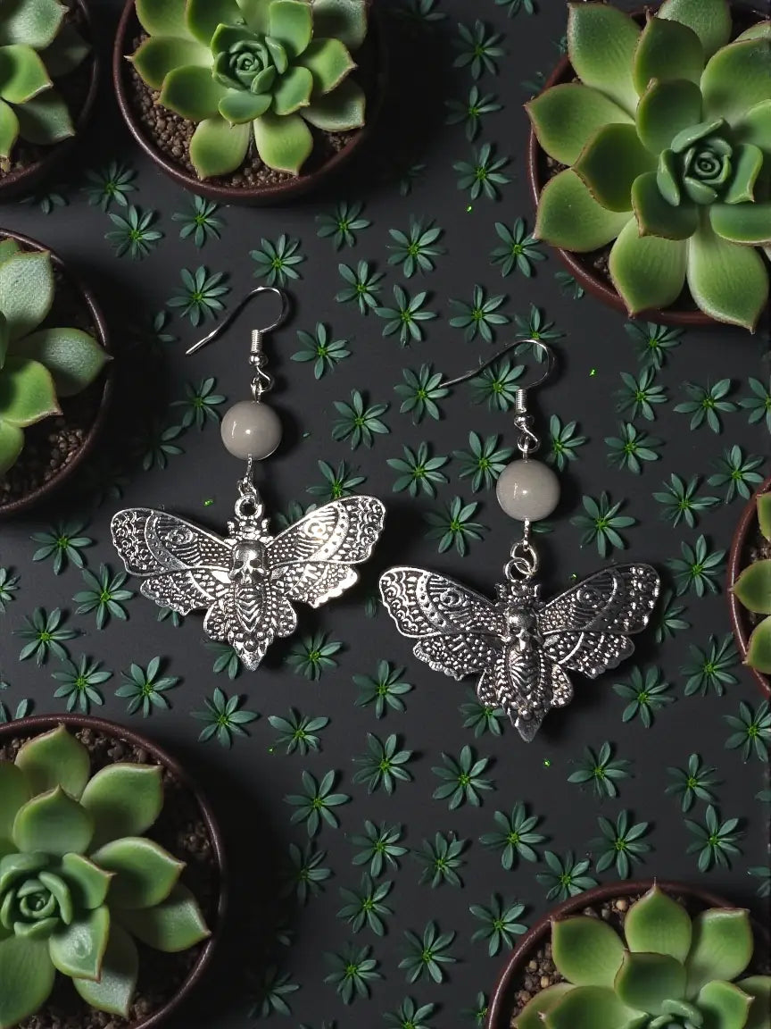 Silver moth earrings with intricate skull centerpiece and round pale gray tagua nut beads detailed design