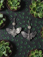 Silver moth earrings with intricate skull centerpiece and round pale gray tagua nut beads detailed design
