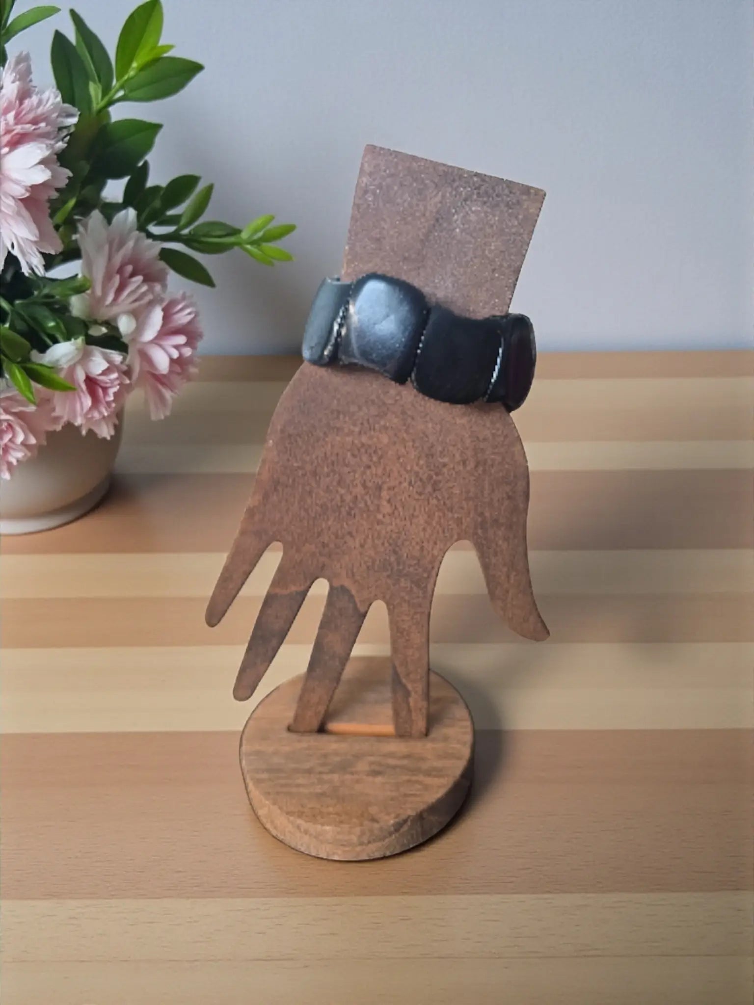 Black leather watch strap with silver buckle on wooden hand stand for midnight black carved tagua nut seed bracelets