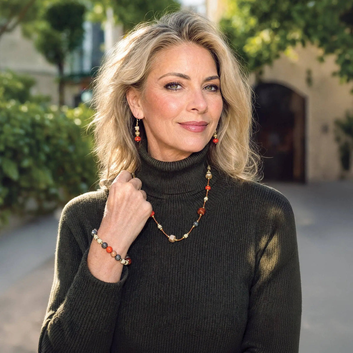 A woman wears a mika bracelet necklace with alternating orange tagua nut beads and gold toned accents