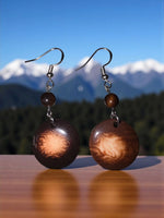Brown circular wooden misty chocolate tagua carved nut earrings with swirling amber pattern and silver hooks from ecuador rainforest