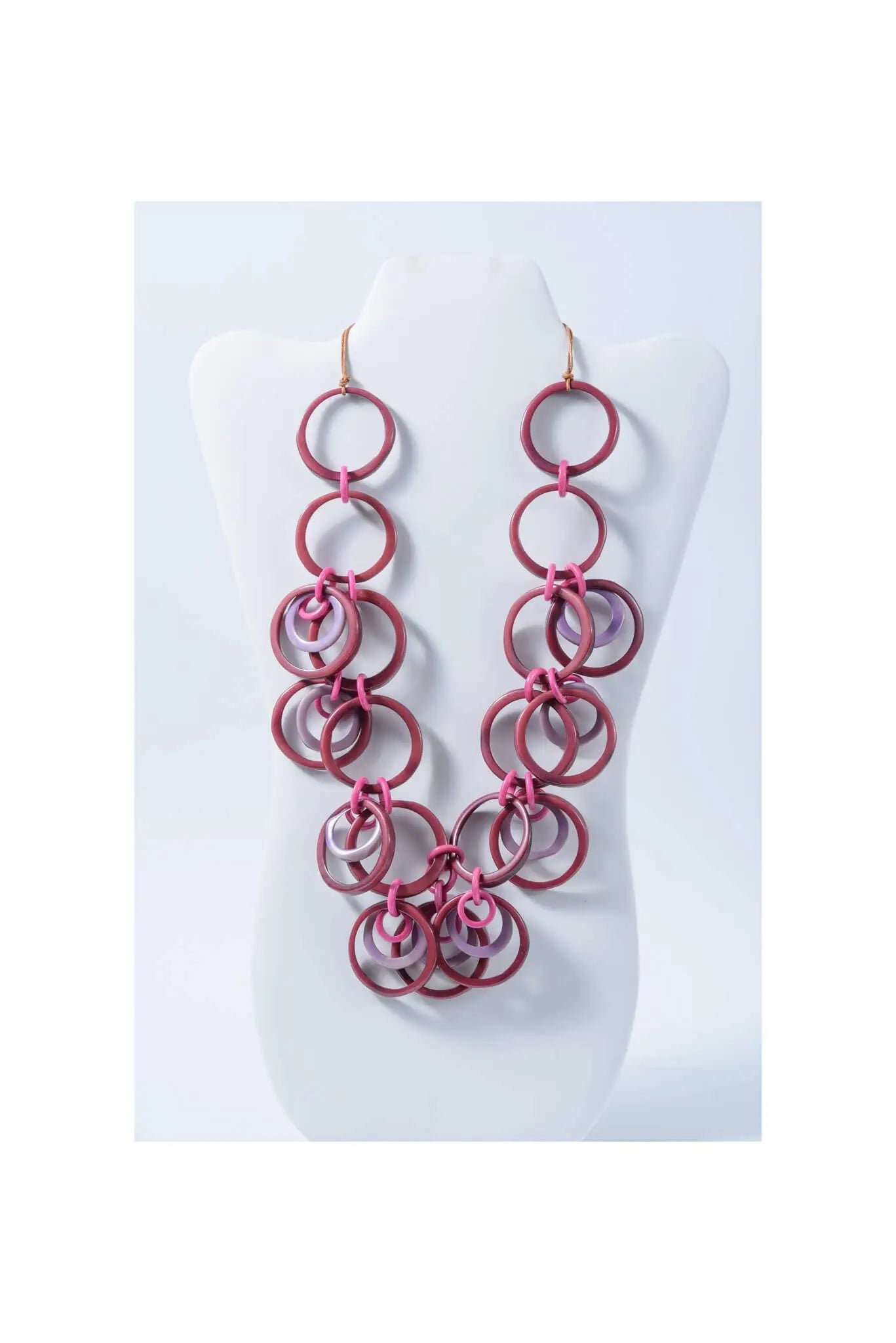 A layered necklace with chunky pink and translucent purple tagua circles hanging from gold-toned hooks