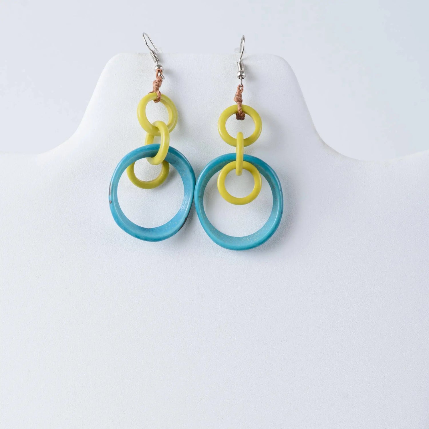 A pair of mona drop and dangle circle statement tagua earrings with bright yellow and translucent turquoise rings