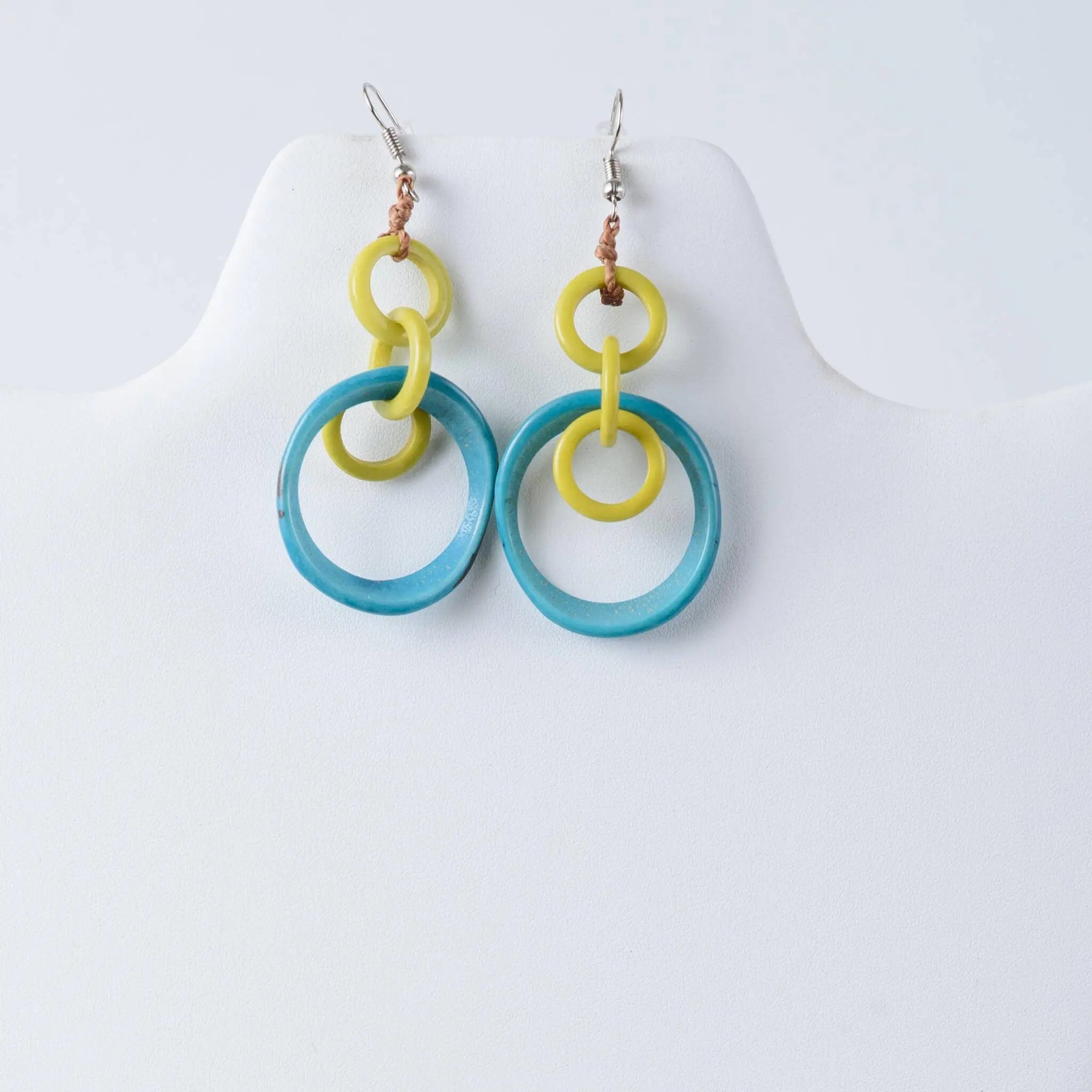 A pair of mona drop and dangle circle statement tagua earrings with bright yellow and translucent turquoise rings