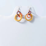 Vibrant multi-colored resin hoop tagua earrings with stacked yellow orange and maroon rings for statement style