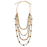 Sun & Wing Studio multi-strand layered statement necklace with mustard, orange, and grey beads on an adjustable cord.