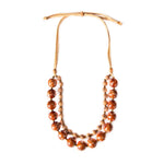 A two-strand necklace with large speckled orange bombona seeds and acai berries beads on tan leather cord