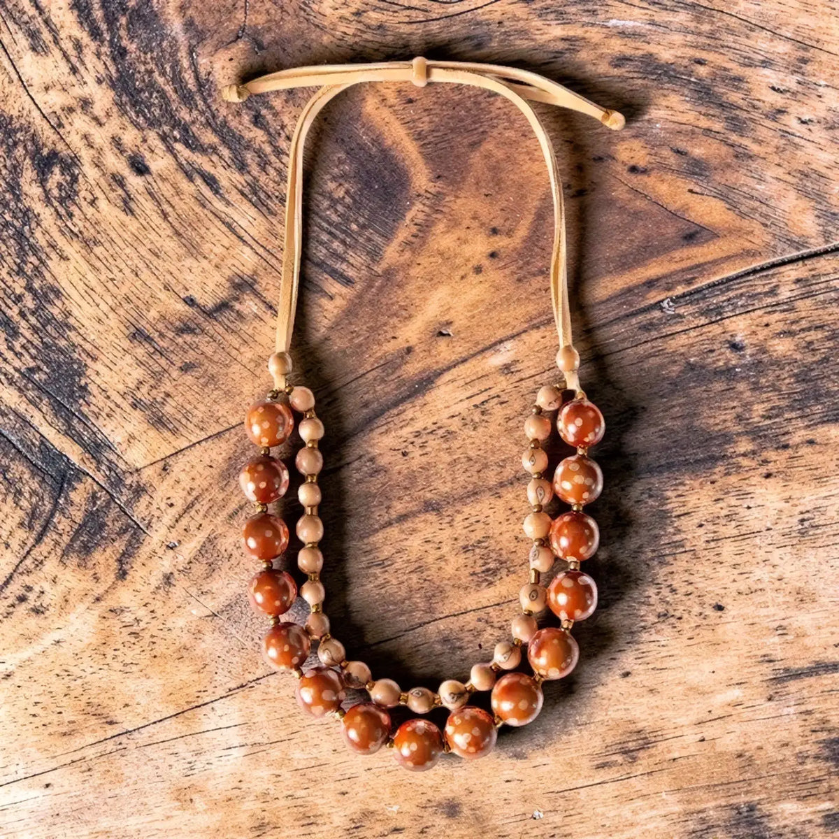 A double strand necklace with polished bombona seeds and acai berries beads on a tan leather cord