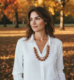 A layered necklace with large glossy amber bombona seeds and smaller cream acai berries in natural tones