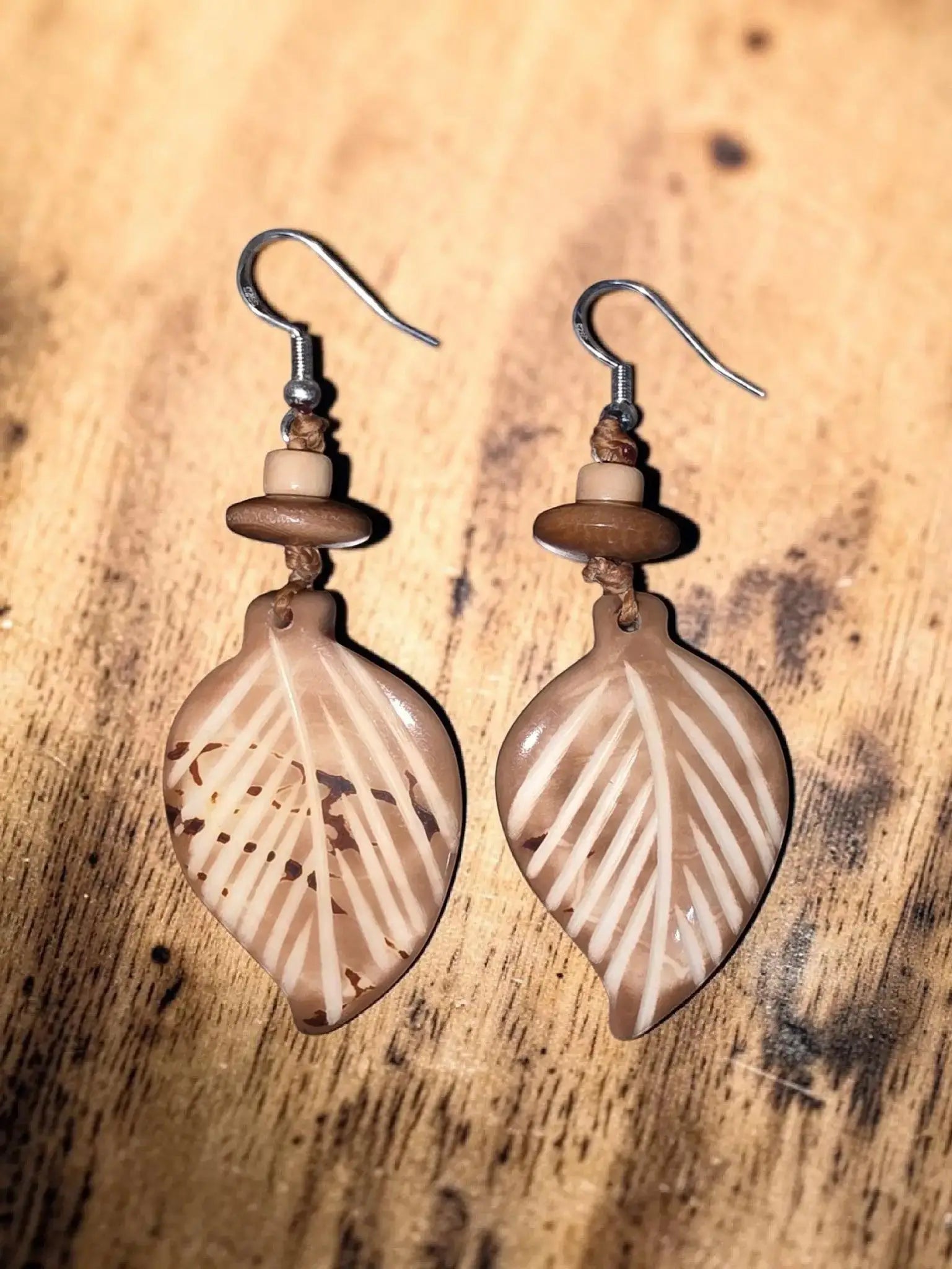 Sun & Wing Studio tan leaf-shaped earrings carved from sustainable Tagua nut with natural wood-toned accents.