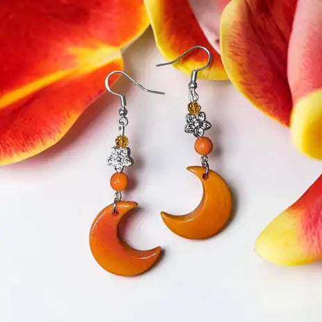 Orange crescent moon earrings with silver hooks and a small crystal flower accent.