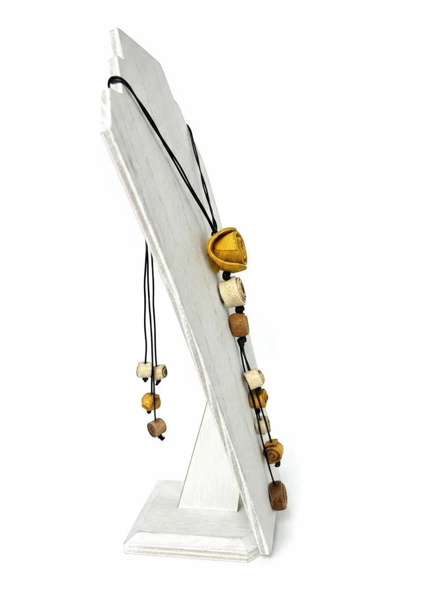 A dainty eco friendly necklace made with cream tan dark brown wooden beads and a golden bell shaped orange peel pendant