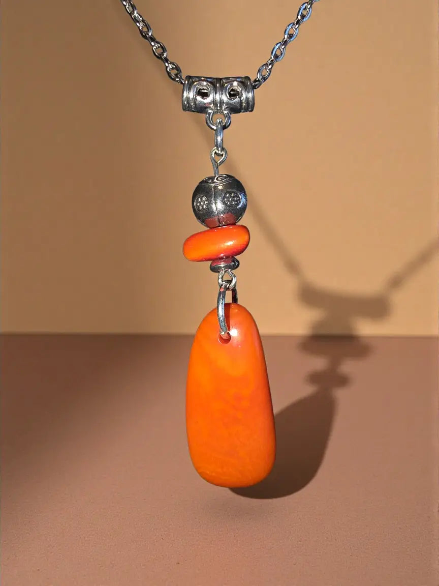 A vibrant orange teardrop amber pendant with ladybug bead on silver chain fair trade necklace from the rainforest