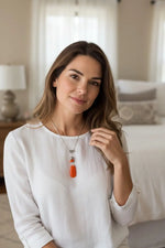 A vibrant orange teardrop pendant necklace with fair trade ladybug bead and silver-toned chain from the rainforest