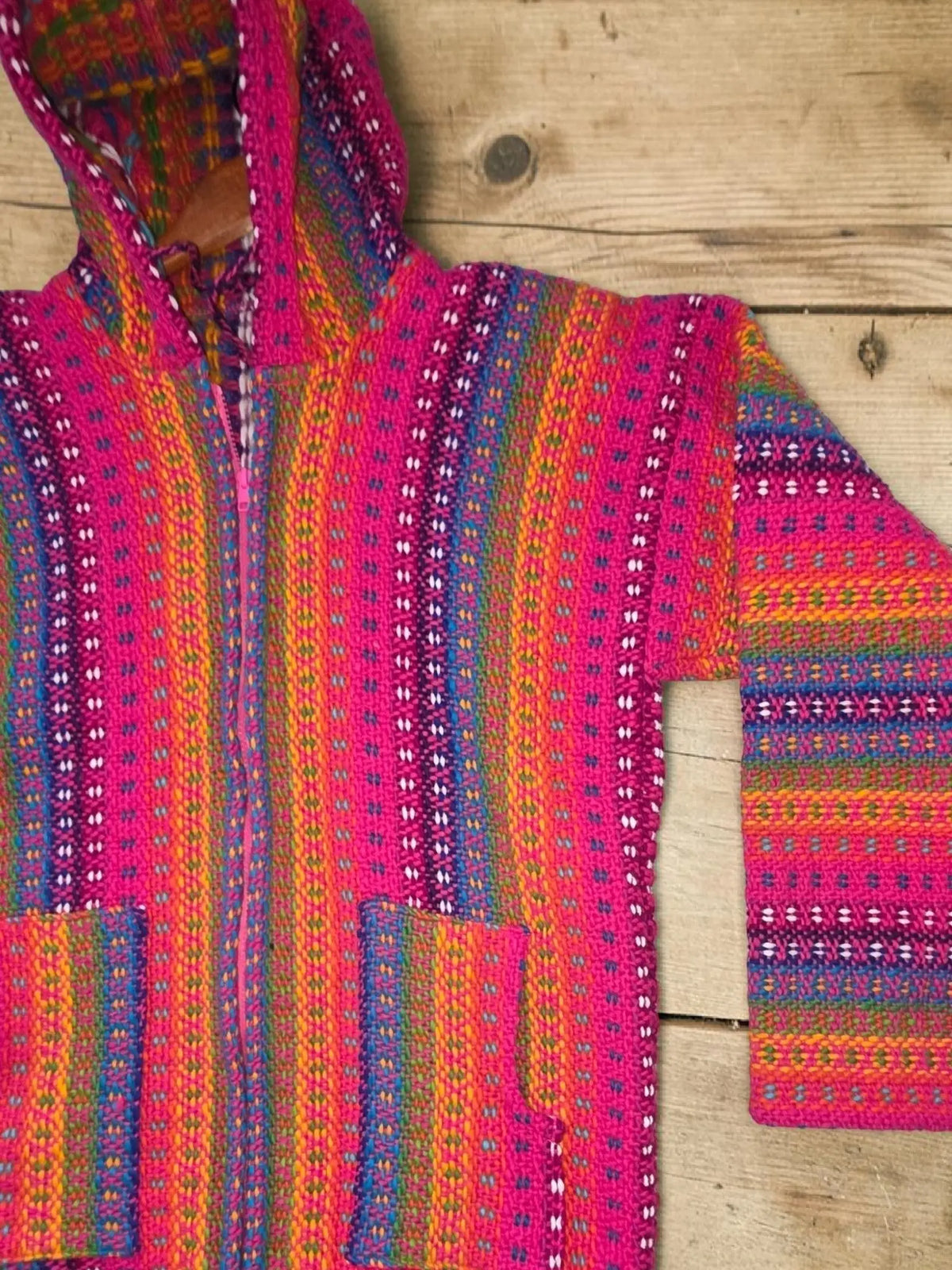 Vibrant pink hoodie cardigan with bold stripes made of 100 percent sheep’s wool showcasing andean textile tradition