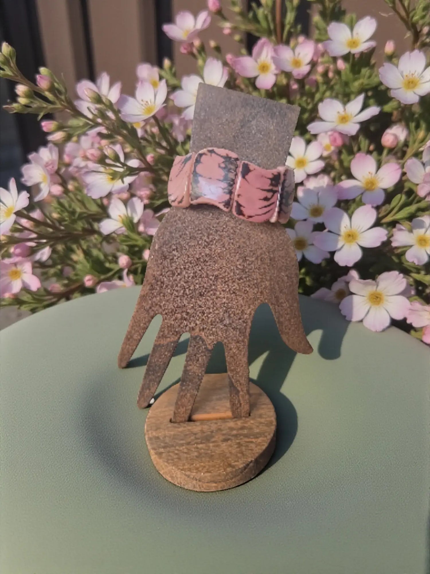 Pink floral-patterned leather watch band on wooden hand stand paired with pink marble natural edge seed bracelets