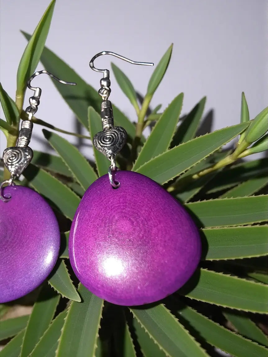 Plum purple sliced tagua nut earrings with teardrop shape and silver-toned hooks featuring swirly heart bead accent