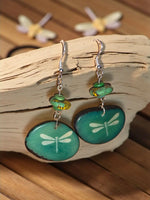 Teal dragonfly-themed pendant earrings with silver hooks and small green beads in turquoise dyed design