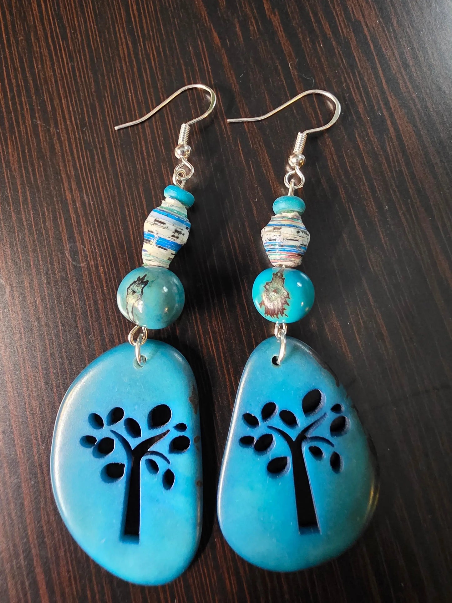 A pair of teal sky blue tree-shaped laser engraved sliced tagua earrings with silver hooks and patterned beads